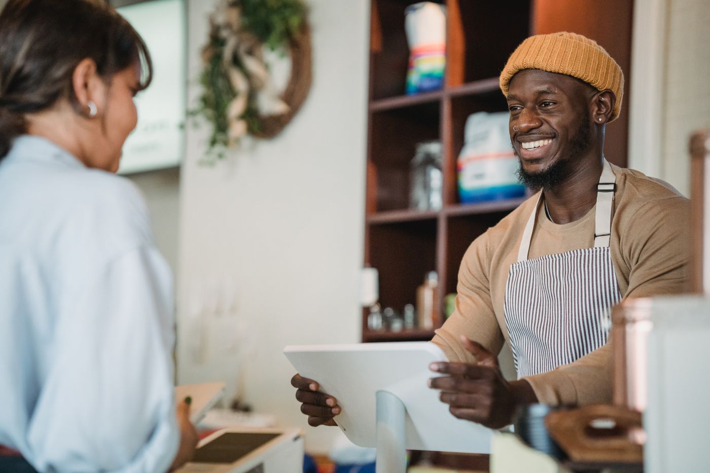 Smiling café owner serving a customer at the counter