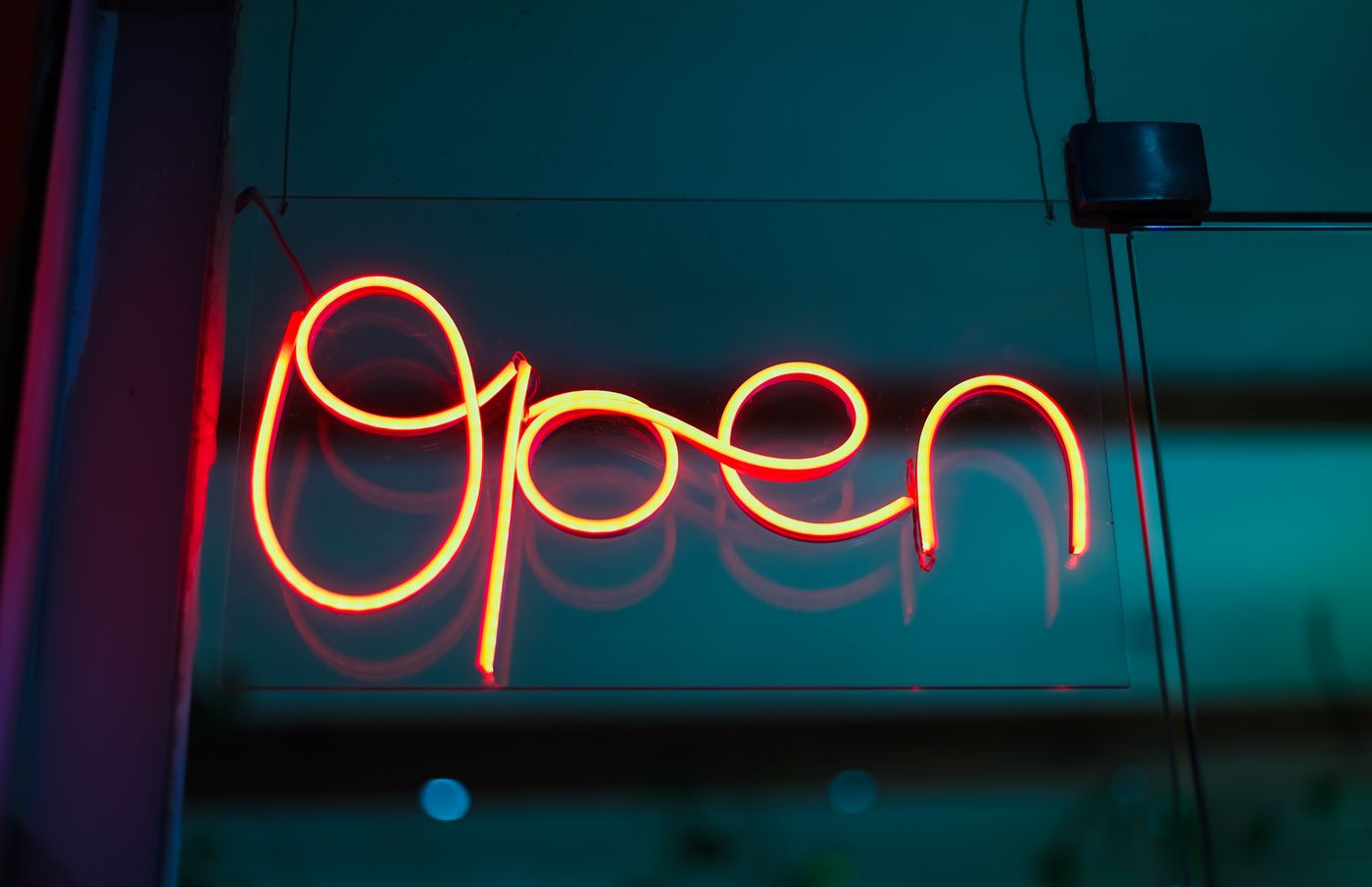 A glowing neon OPEN sign in a dark shop window